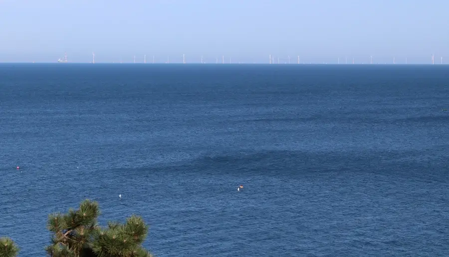 Bild auf Windräder am Horizont am Meer in der Normandie zum Thema Herausforderungen